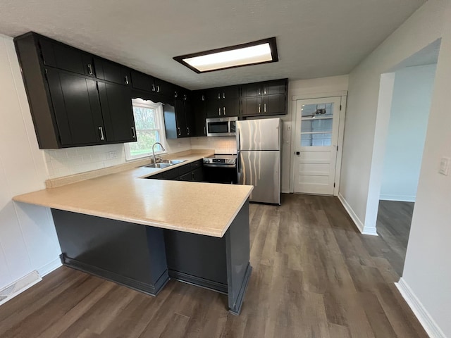 kitchen with sink, stainless steel appliances, dark hardwood / wood-style floors, backsplash, and kitchen peninsula