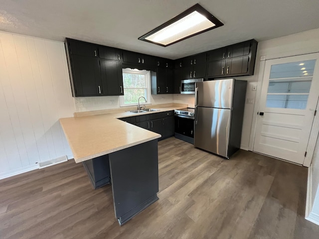 kitchen with kitchen peninsula, light wood-type flooring, and stainless steel appliances