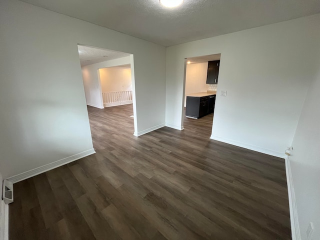 empty room featuring a textured ceiling and dark wood-type flooring