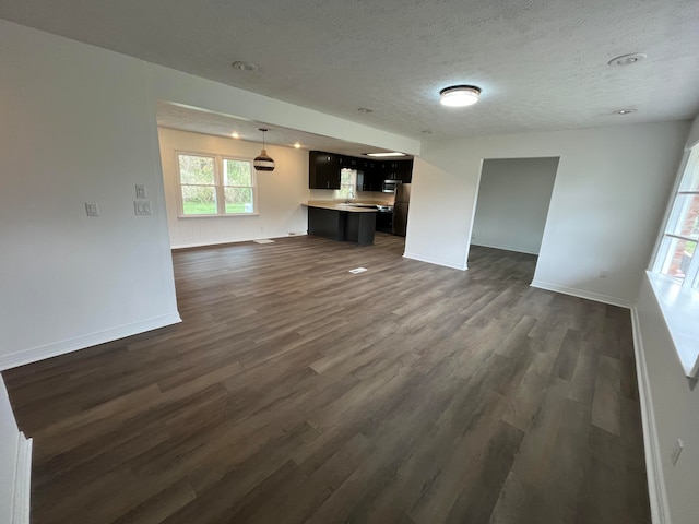 unfurnished living room with a textured ceiling and dark wood-type flooring