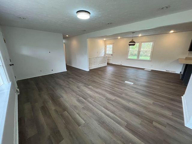 unfurnished living room with a textured ceiling and dark hardwood / wood-style floors