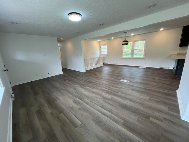 unfurnished living room featuring a textured ceiling and dark hardwood / wood-style floors