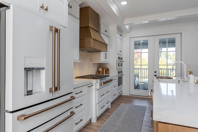 kitchen with white cabinetry, light wood-type flooring, high end white fridge, custom range hood, and ornamental molding