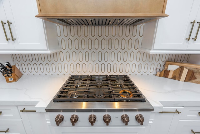 kitchen featuring custom exhaust hood, light stone counters, white cabinetry, and backsplash