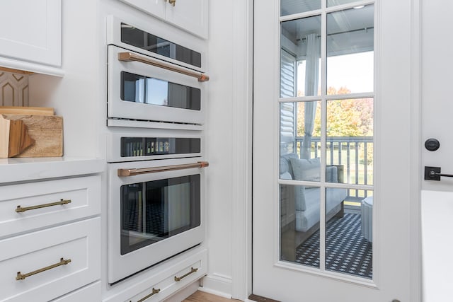 kitchen with white cabinetry, stainless steel double oven, and light wood-type flooring