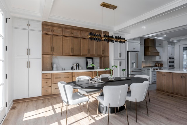 kitchen with premium range hood, light hardwood / wood-style floors, decorative light fixtures, high end white refrigerator, and decorative backsplash