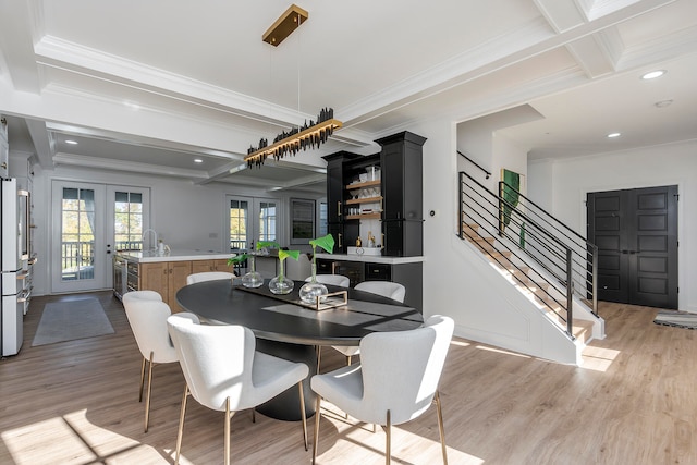 dining space with crown molding, french doors, beamed ceiling, and light wood-type flooring