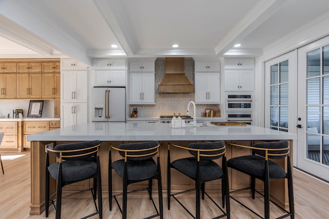 kitchen featuring custom range hood, white appliances, a spacious island, light hardwood / wood-style flooring, and white cabinetry