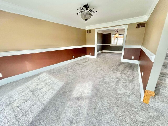 carpeted spare room featuring crown molding and a notable chandelier