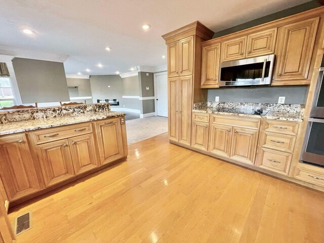 kitchen with kitchen peninsula, stainless steel appliances, a breakfast bar area, and light hardwood / wood-style flooring