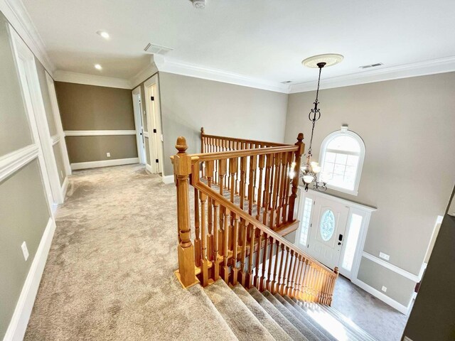 stairway featuring carpet flooring, ornamental molding, and a notable chandelier