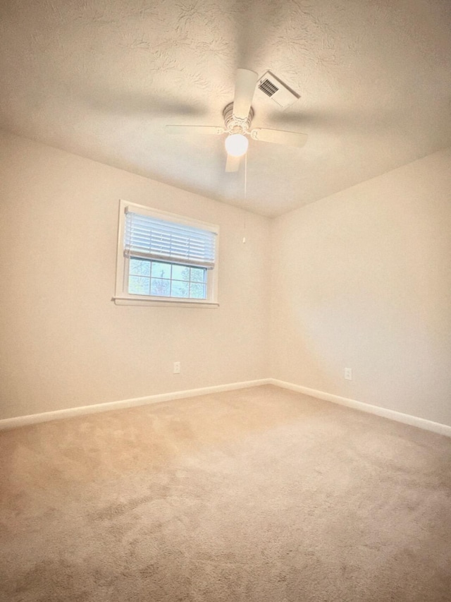 empty room with ceiling fan, carpet floors, and a textured ceiling