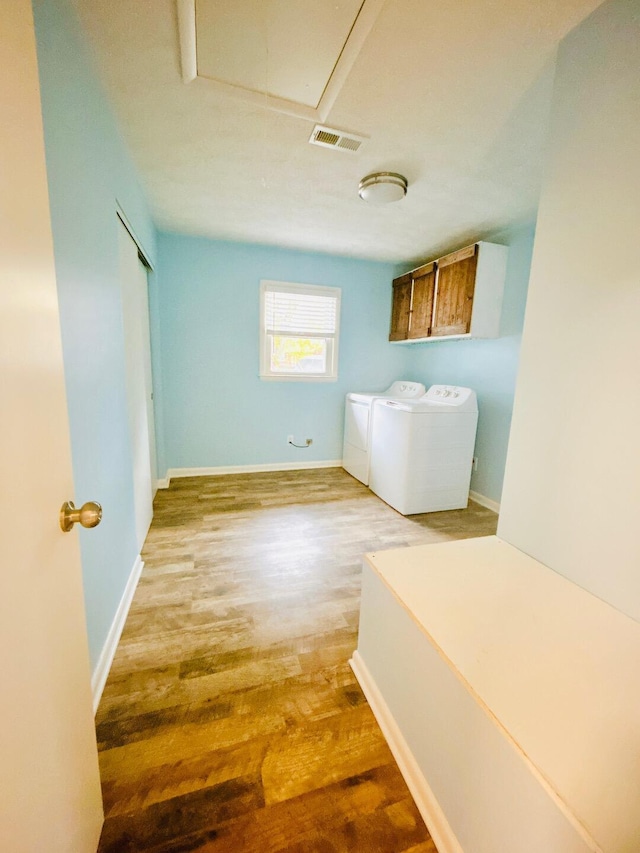 laundry room with washer and dryer, light hardwood / wood-style flooring, and cabinets