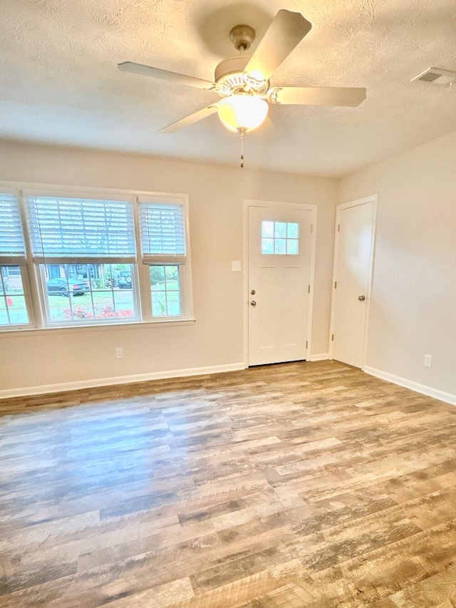 empty room featuring ceiling fan, a textured ceiling, and light hardwood / wood-style flooring