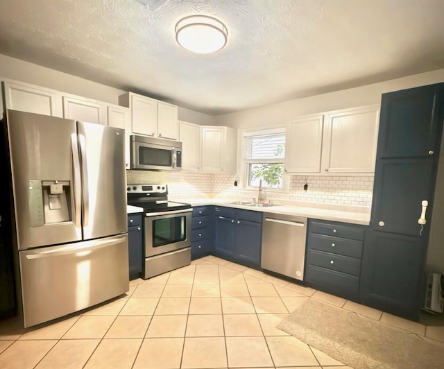 kitchen featuring backsplash, white cabinets, sink, light tile patterned floors, and stainless steel appliances