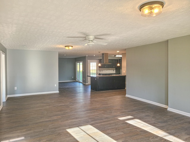 unfurnished living room featuring ceiling fan, dark wood-type flooring, and a textured ceiling