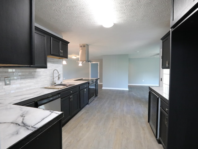 kitchen featuring sink, island exhaust hood, a textured ceiling, appliances with stainless steel finishes, and light wood-type flooring