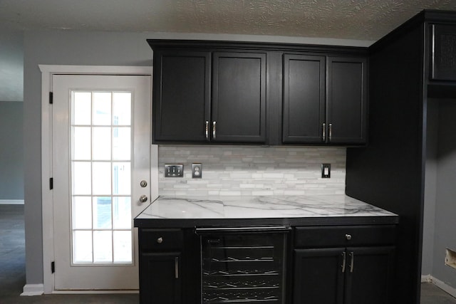 bar with a textured ceiling, light stone counters, and backsplash