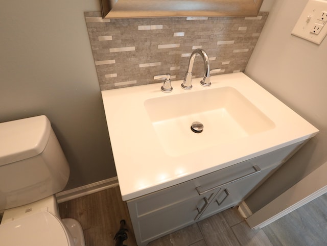 bathroom with decorative backsplash, hardwood / wood-style floors, vanity, and toilet