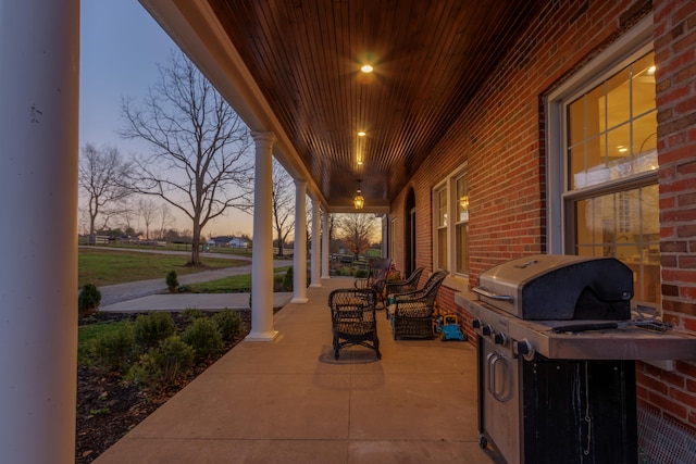 patio terrace at dusk featuring a porch and area for grilling