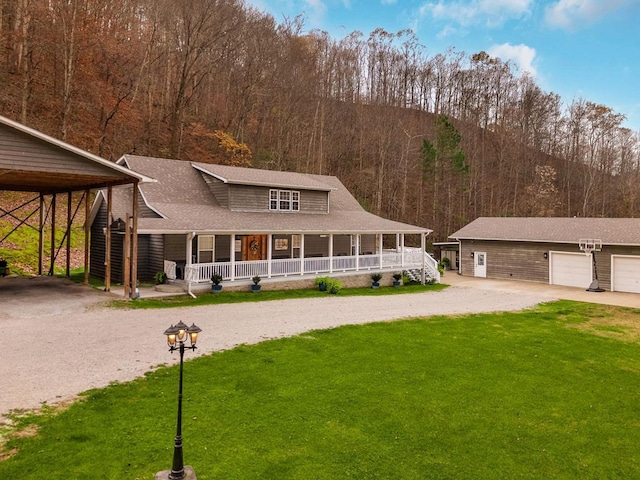 farmhouse-style home featuring a front yard, a carport, a porch, an outbuilding, and a garage