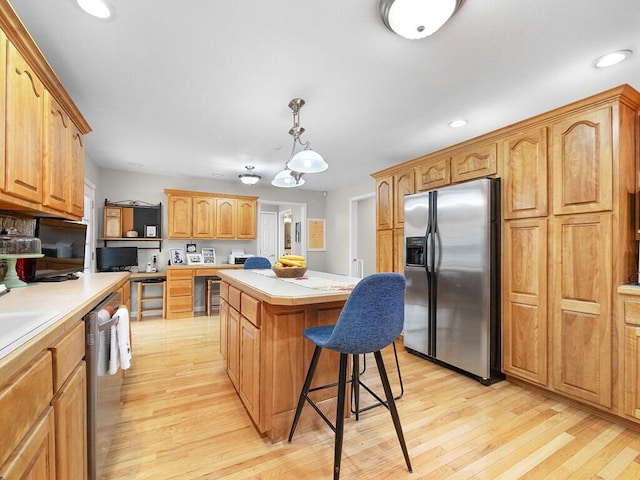 kitchen with stainless steel appliances, light hardwood / wood-style flooring, decorative light fixtures, a kitchen bar, and a kitchen island