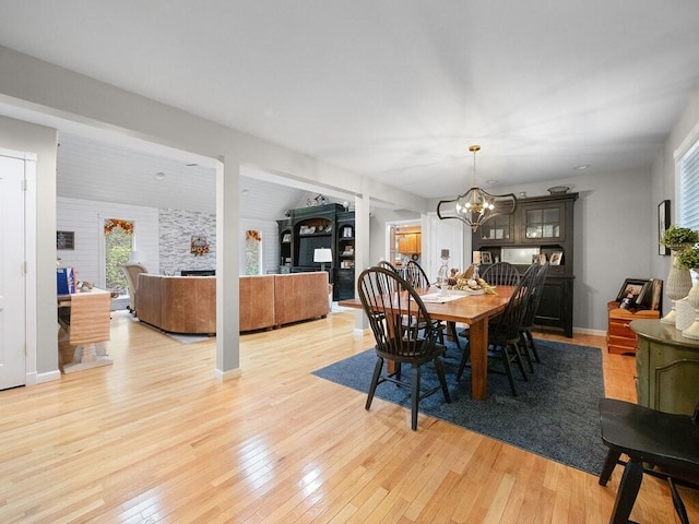 dining area featuring light hardwood / wood-style floors, vaulted ceiling, brick wall, and an inviting chandelier