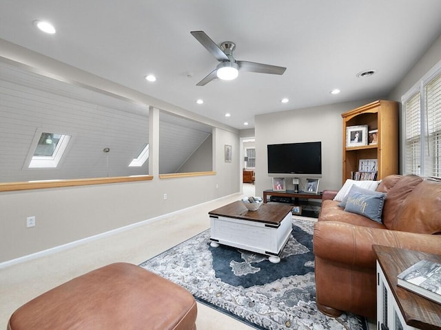 living room featuring carpet flooring, ceiling fan, and a skylight