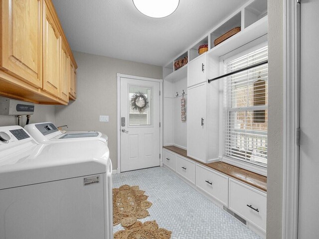 clothes washing area with washing machine and dryer and cabinets