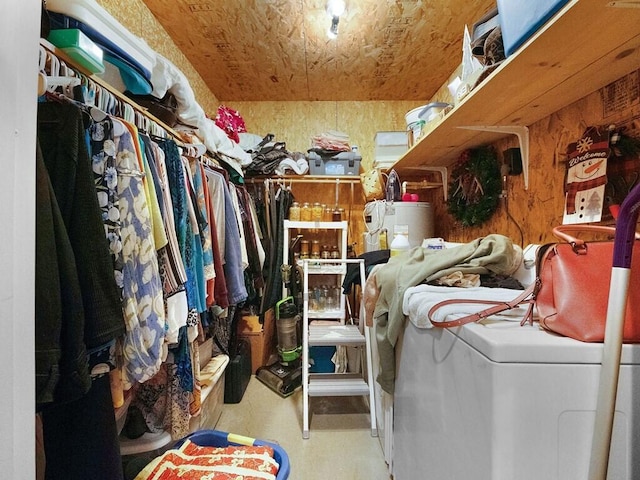 clothes washing area featuring wood walls and water heater