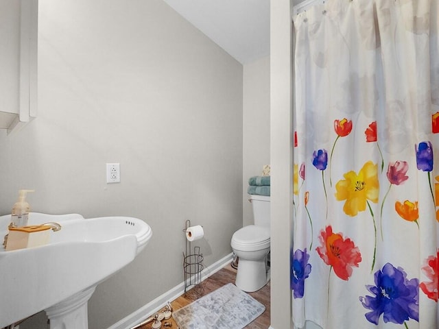 bathroom featuring walk in shower, sink, hardwood / wood-style floors, and toilet