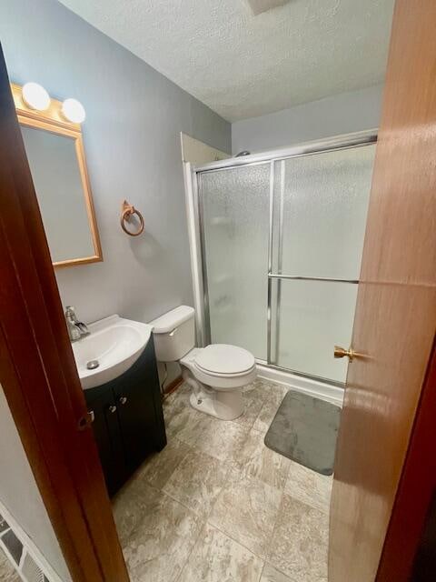 bathroom with toilet, vanity, a textured ceiling, and walk in shower