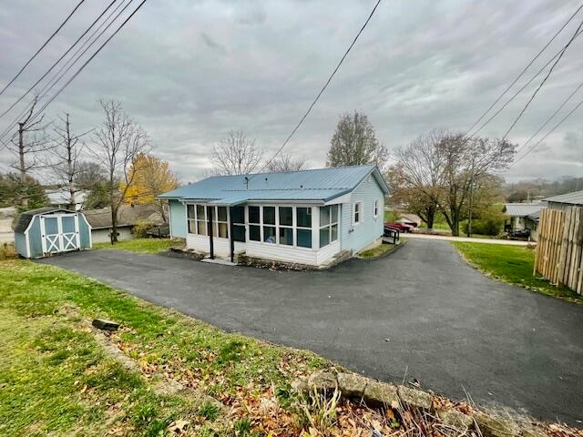 rear view of property with a storage shed and a sunroom