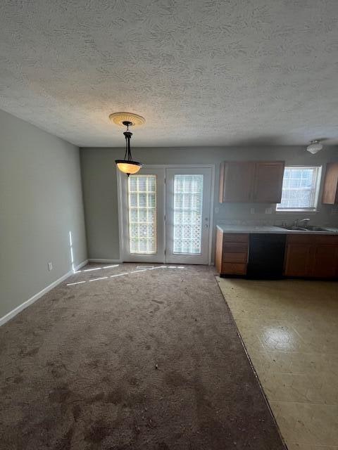 kitchen featuring sink, decorative light fixtures, light colored carpet, and a textured ceiling