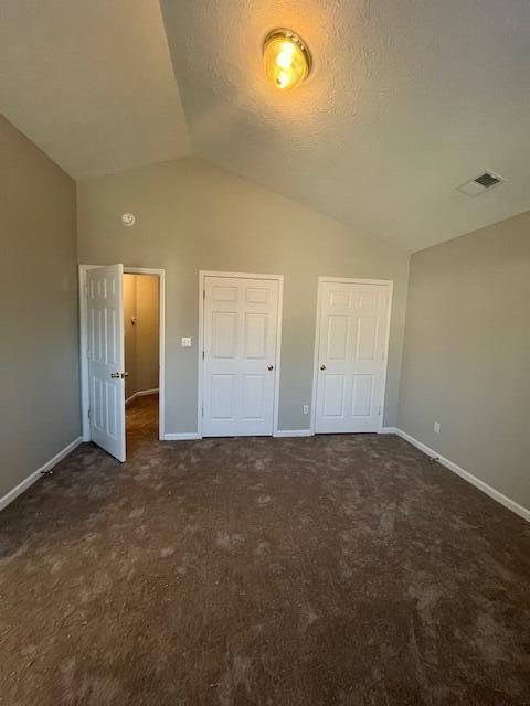 unfurnished bedroom featuring dark carpet and lofted ceiling