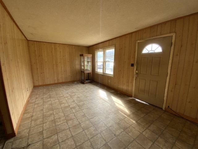 foyer entrance featuring a textured ceiling, plenty of natural light, and wood walls