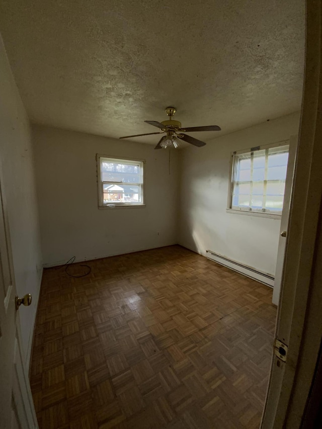 spare room with ceiling fan, dark parquet floors, a baseboard radiator, and a textured ceiling