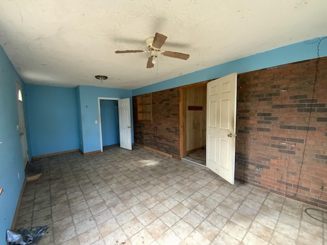 unfurnished bedroom with ceiling fan and brick wall