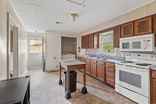 kitchen featuring washer and dryer, white appliances, and sink