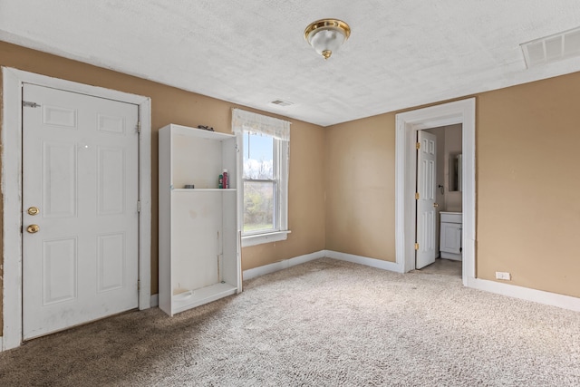 unfurnished bedroom with connected bathroom, light colored carpet, and a textured ceiling