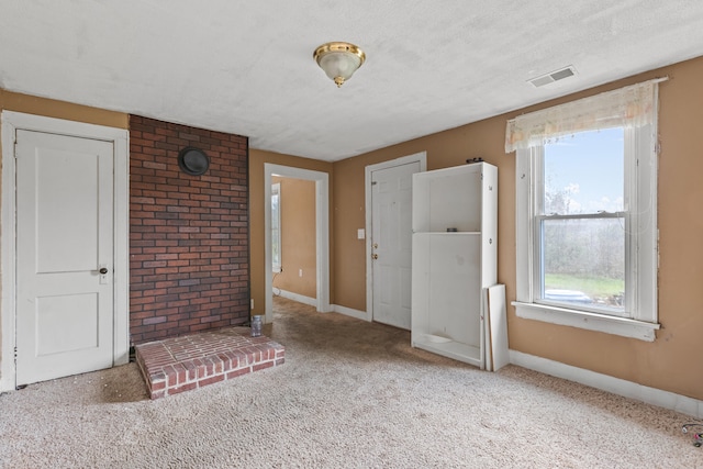 unfurnished living room featuring light carpet, a healthy amount of sunlight, and a textured ceiling