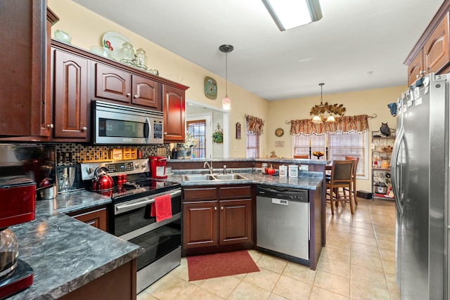 kitchen with sink, stainless steel appliances, kitchen peninsula, decorative light fixtures, and light tile patterned floors