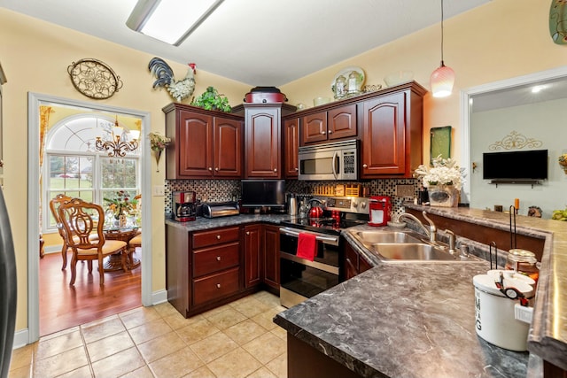 kitchen featuring sink, decorative light fixtures, decorative backsplash, light tile patterned floors, and appliances with stainless steel finishes