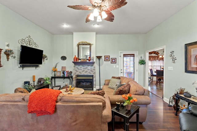 living room with dark hardwood / wood-style floors, ceiling fan, and a fireplace