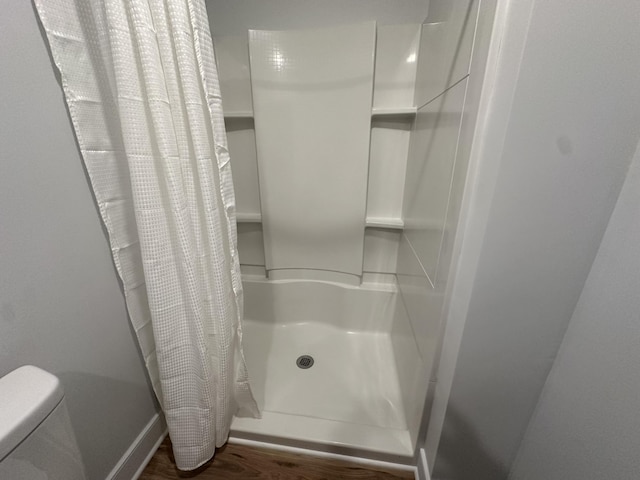 bathroom with hardwood / wood-style floors, toilet, and walk in shower