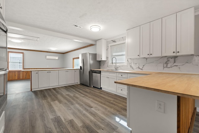 kitchen featuring kitchen peninsula, stainless steel appliances, white cabinetry, and light hardwood / wood-style flooring