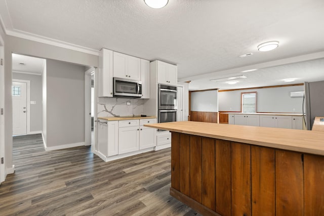 kitchen featuring white cabinetry, wood counters, dark hardwood / wood-style floors, appliances with stainless steel finishes, and ornamental molding