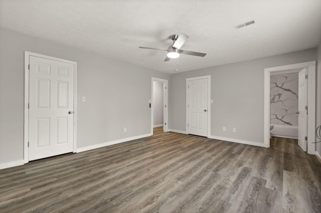 unfurnished bedroom featuring a textured ceiling, connected bathroom, ceiling fan, and dark wood-type flooring