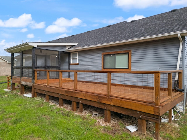 back of property featuring a deck, a lawn, and a sunroom