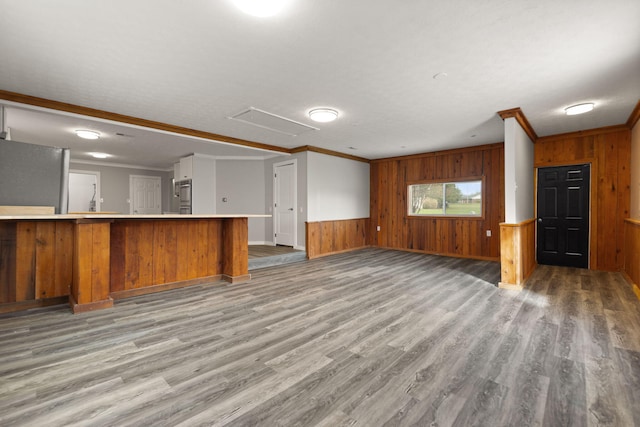 kitchen with wood walls, kitchen peninsula, ornamental molding, and light hardwood / wood-style flooring